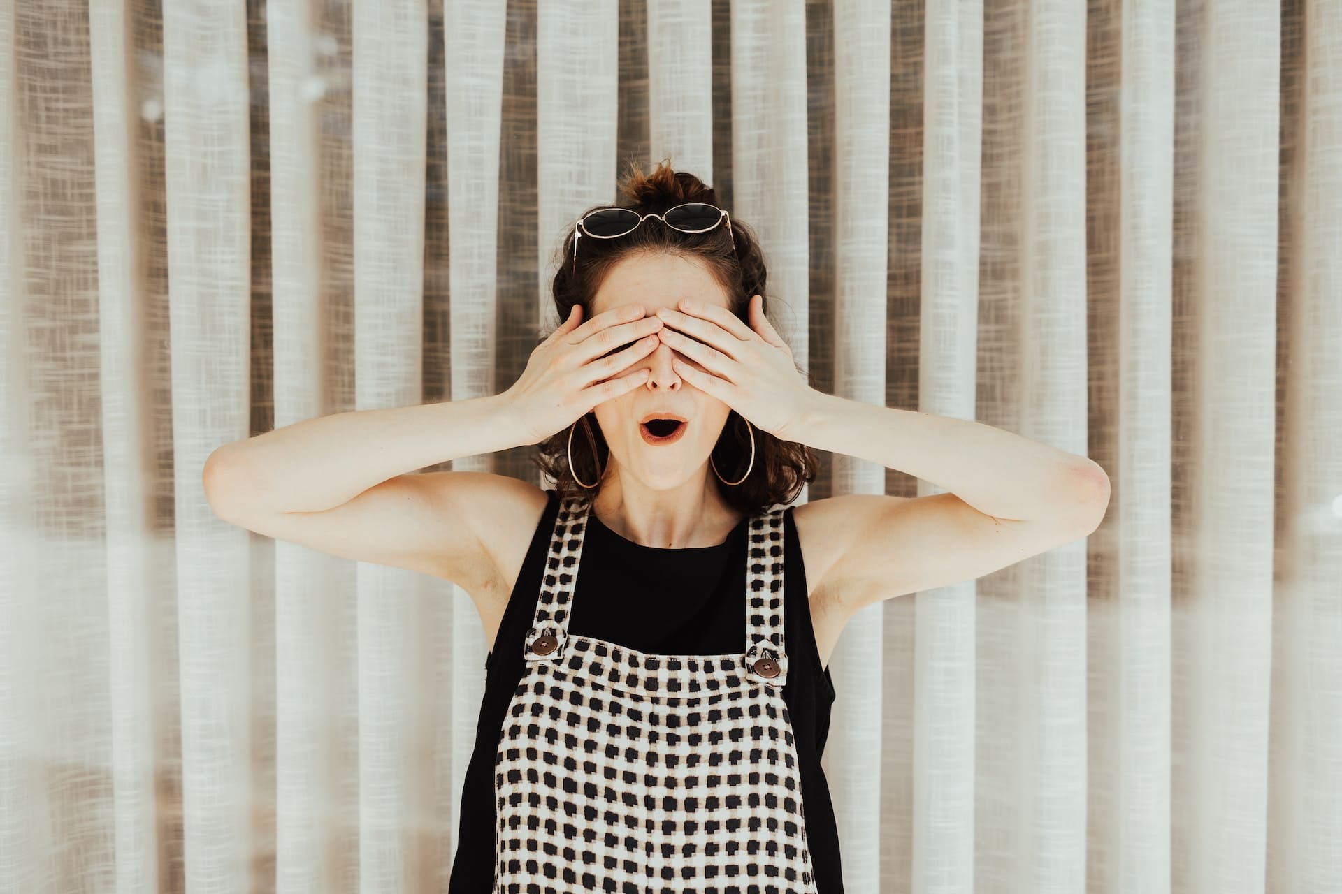 A young lady holds her hands over her eyes to show the idea of using a pen name (a made-up name authors use to disguise their identity).