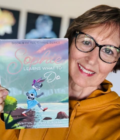 Pam Burgess holds her latest children's book, Sophie Learns What to Do
