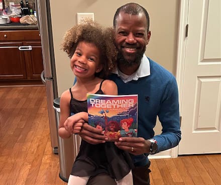 Dr. Frank Clark and his daughter, Claire, holding the book they coauthored, Dreaming Together.