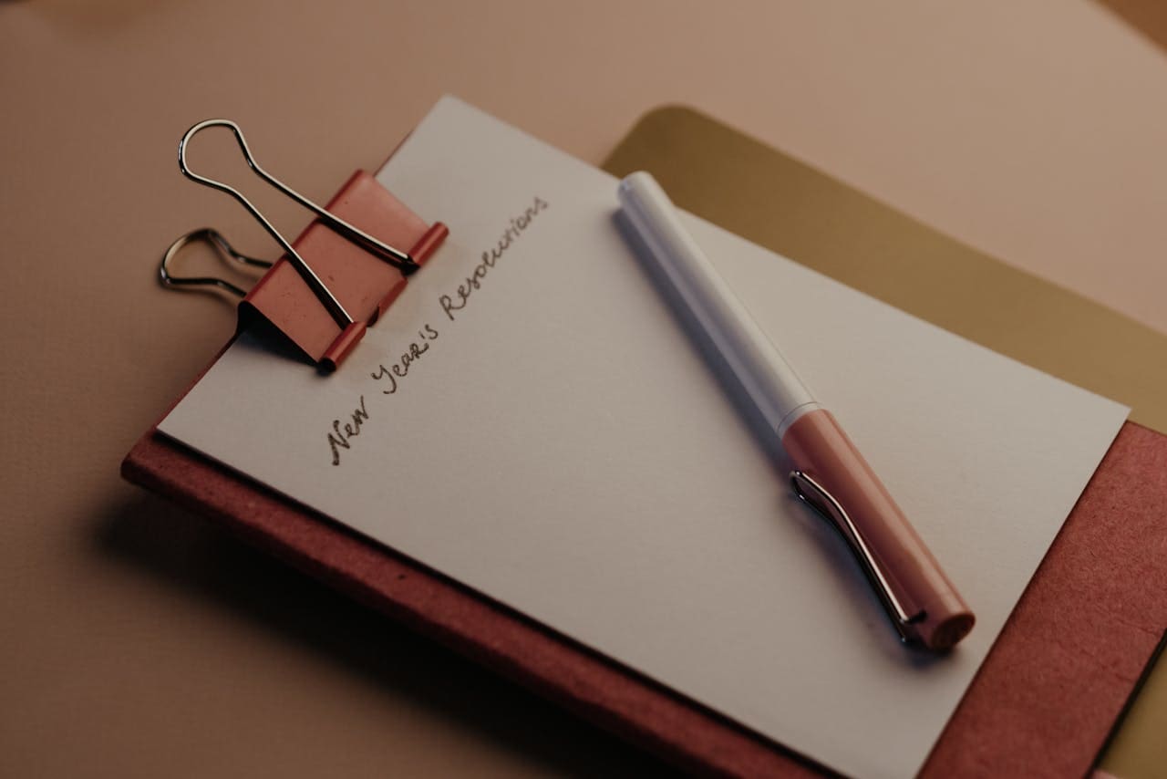 A notepad reads New Year's Resolutions, illustrating resolutions for writers